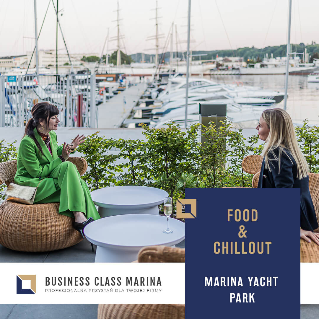 BCM - widok strony internetowej na ekranie laptopa, który stoi na stoliku. W tle widać marinę jachtową